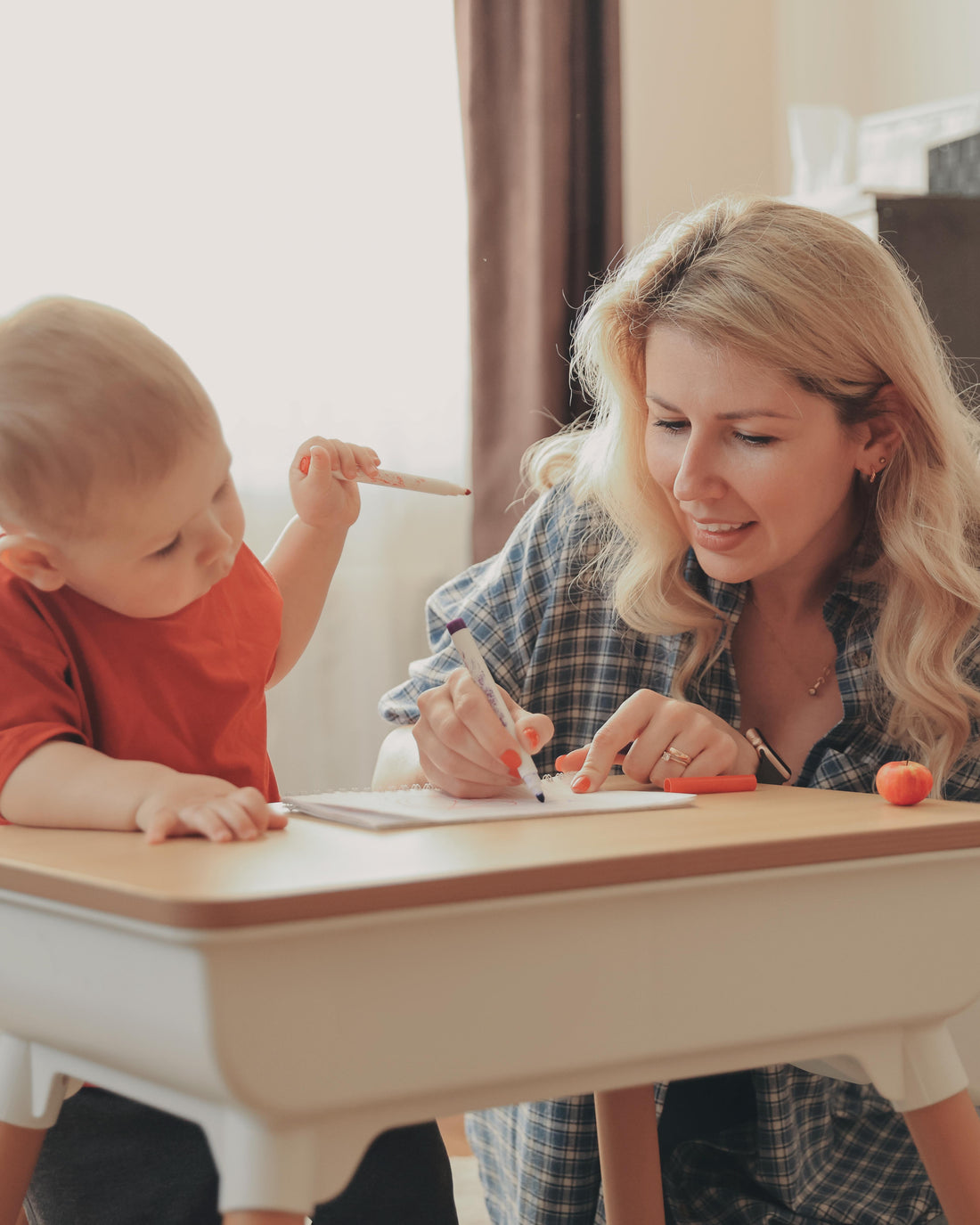 Mother teaching her son to draw at a small table