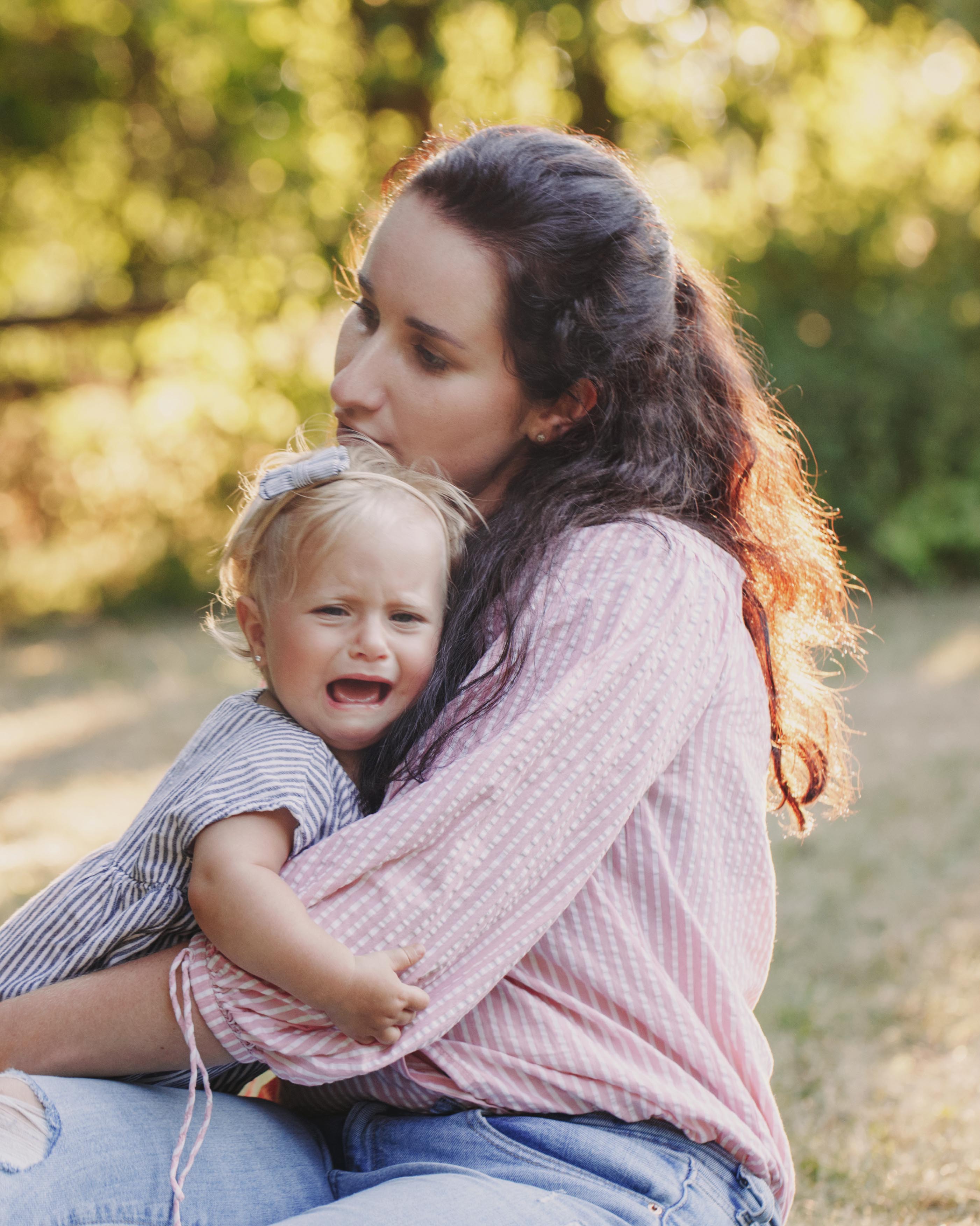 Mother comforting a crying toddler with a warm hug