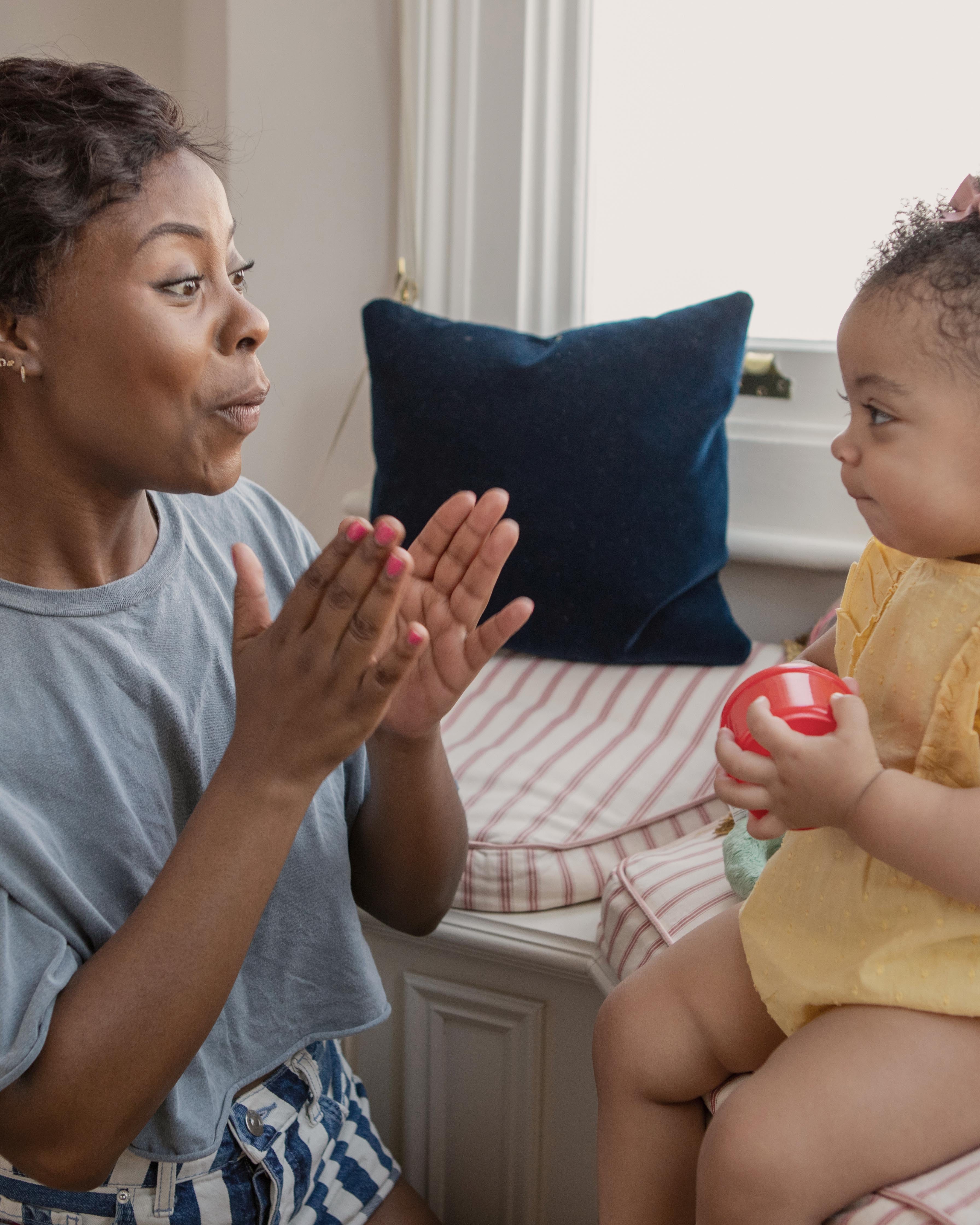 Mother playing with baby daughter at home
