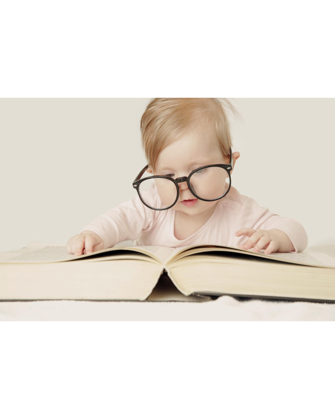 Baby sitting in front of a big book