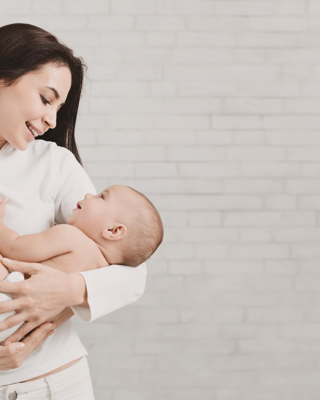 Young mother tenderly hugging her newborn