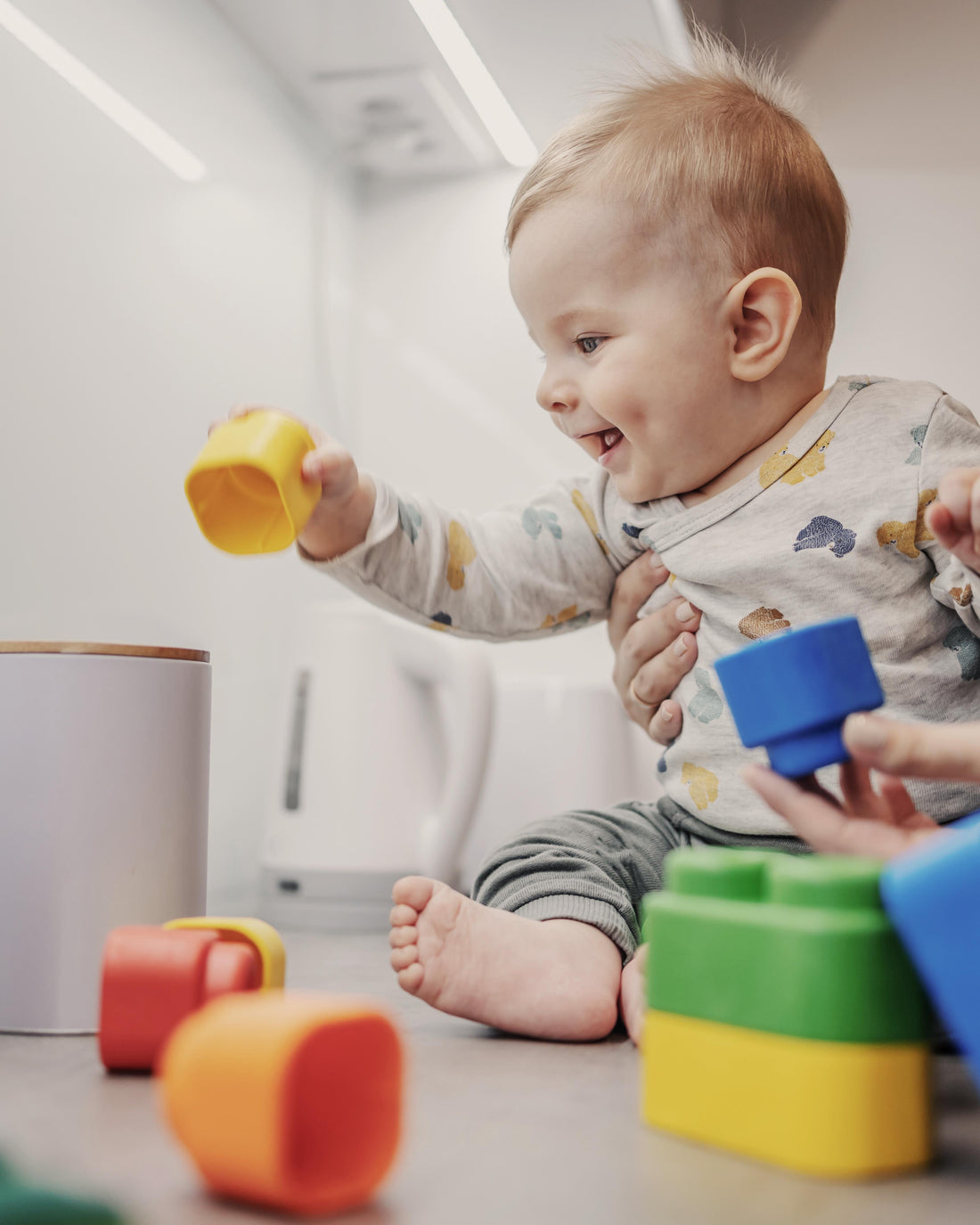 Smiling toddler boy playing with blocks with his mother