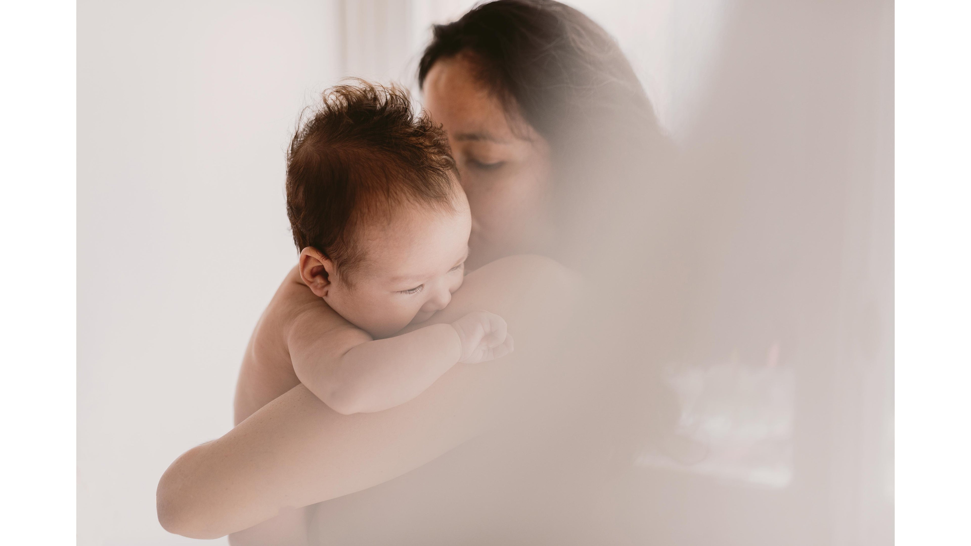 Mother tenderly holding her newborn baby with soft natural light