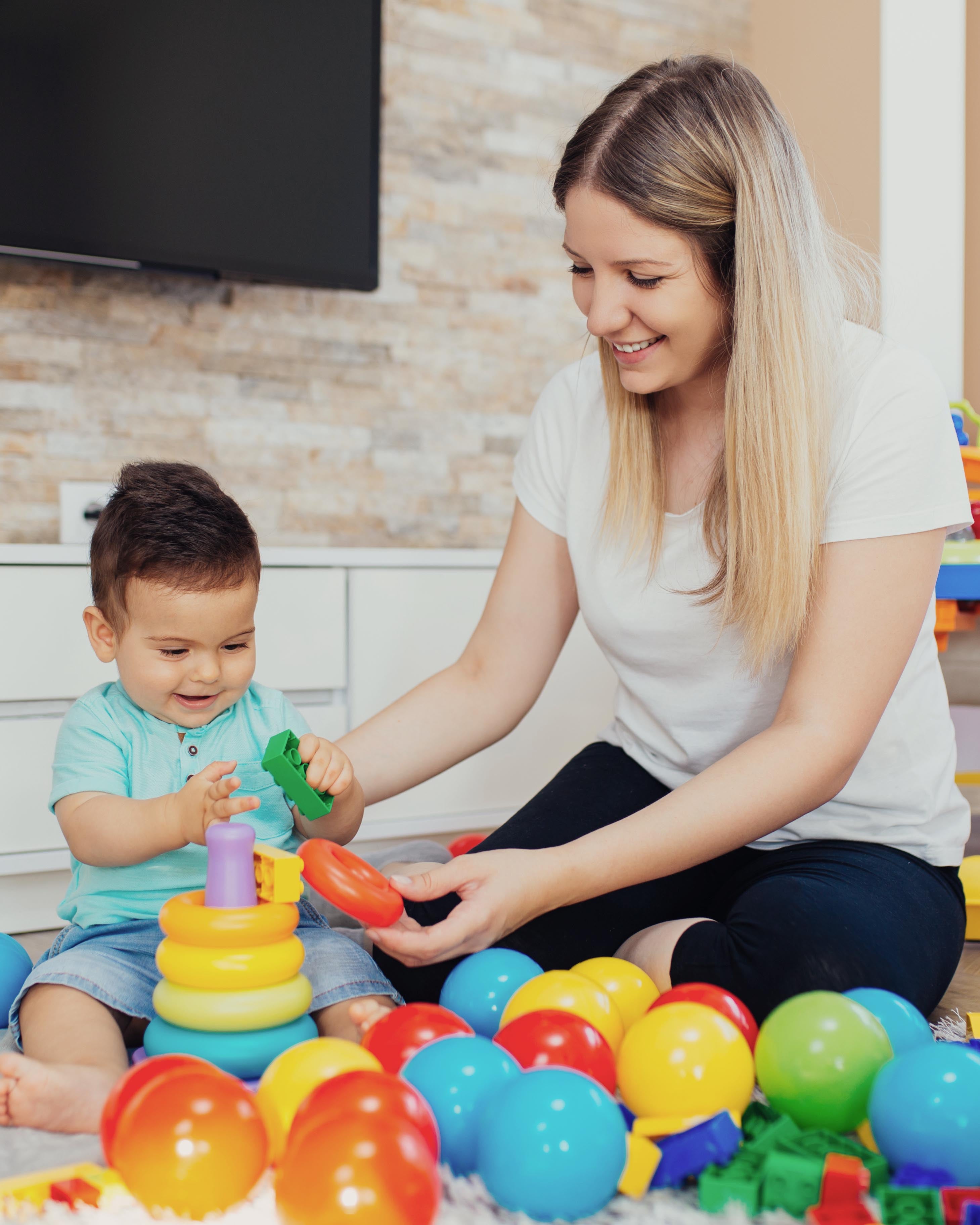 Happy mother playing with her little son at home