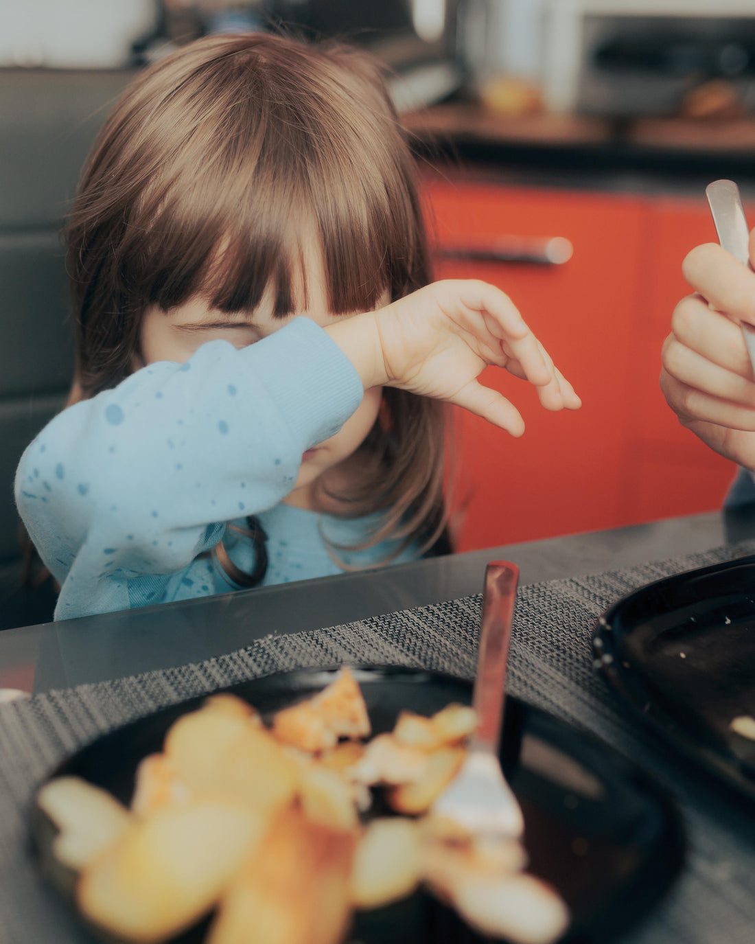 Toddler girl at the table not wanting to eat lunch