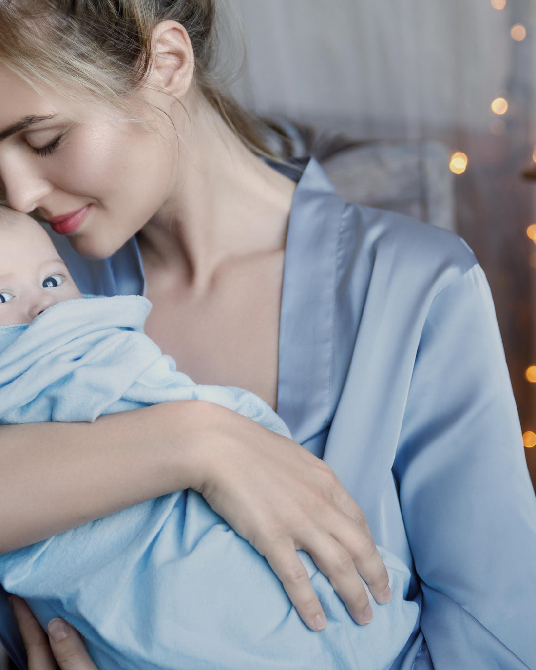 Young mother with her baby wrapped in a soft blue cloth