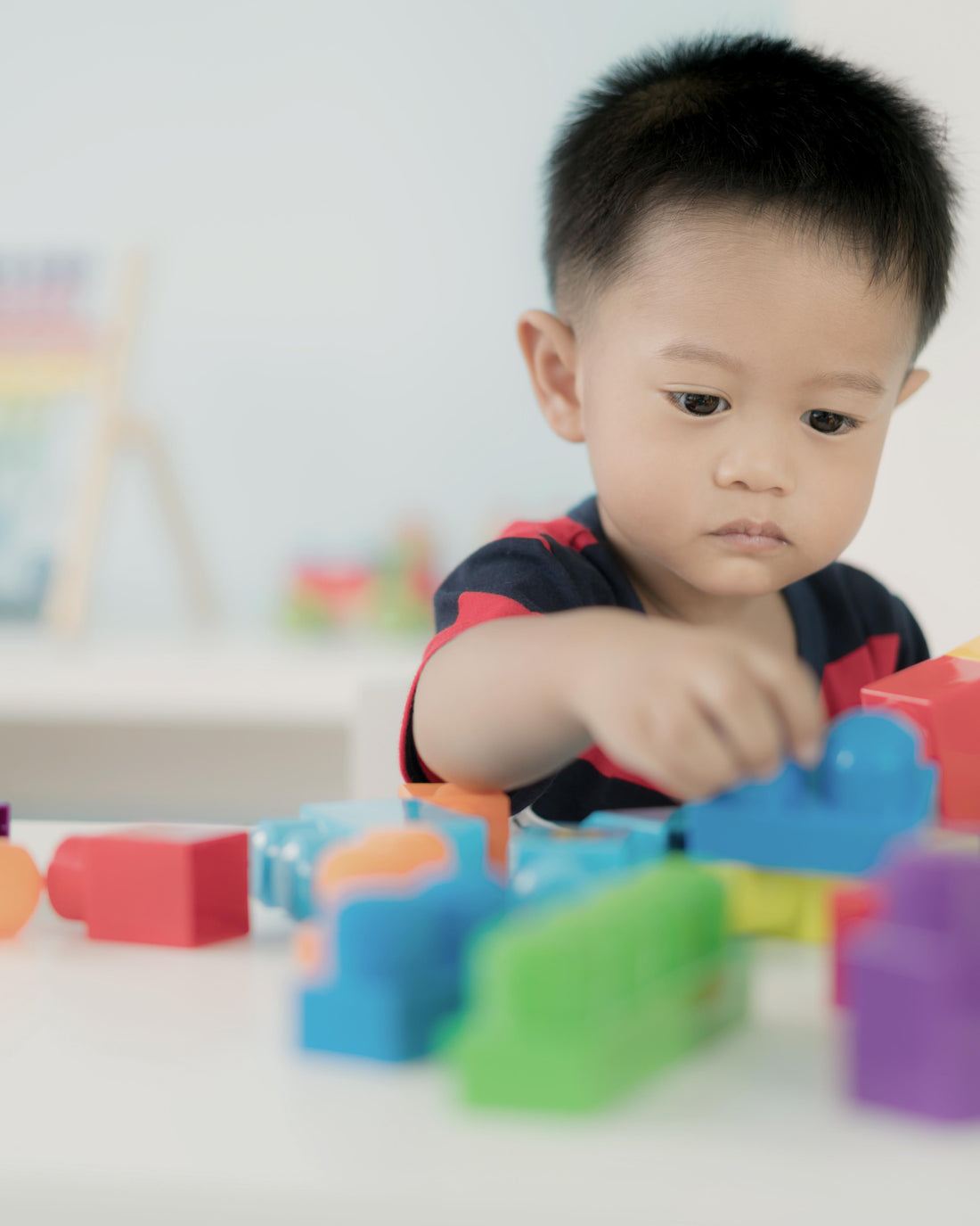 Toddler boy playing with colorful block toys at home