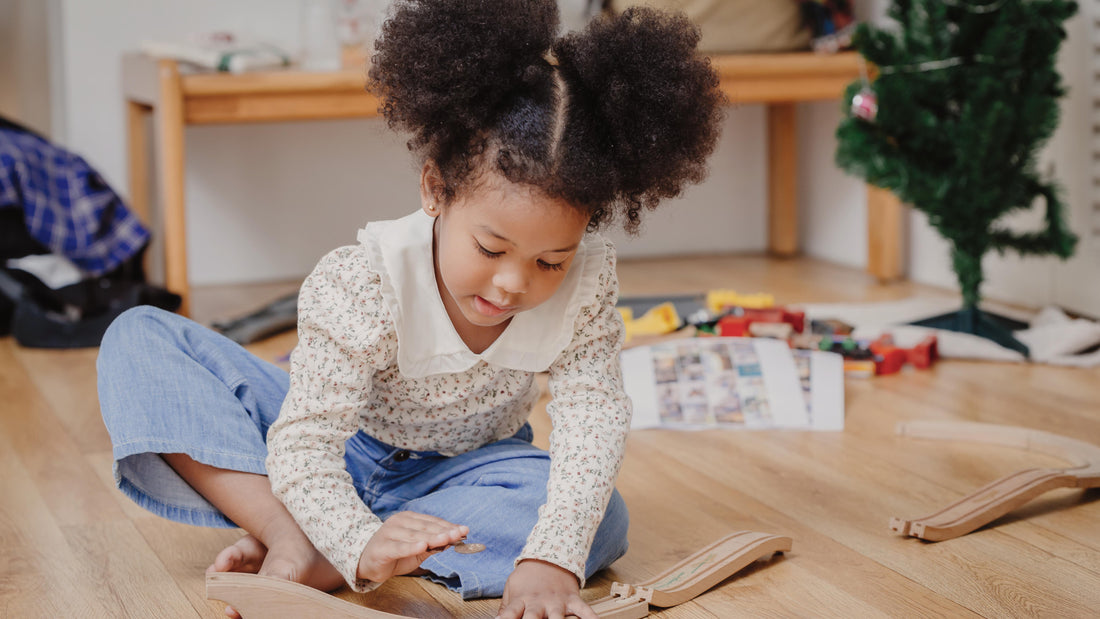 Toddler girl playing calmly with wooden train tracks at home