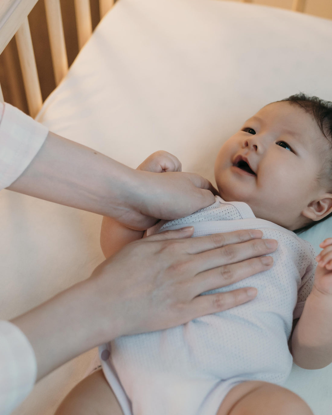 Parent gently soothing baby to sleep in crib
