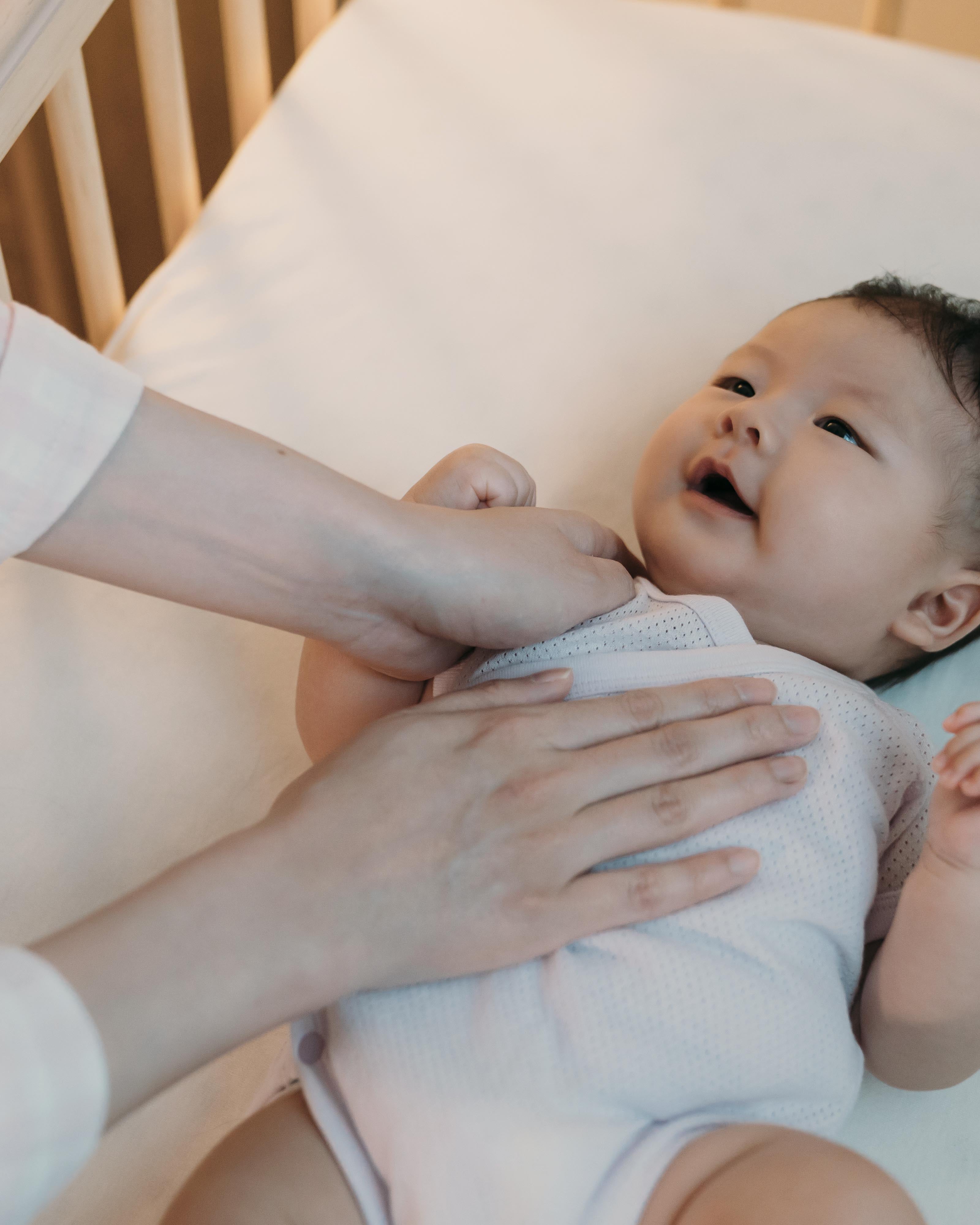Parent gently soothing baby to sleep in crib