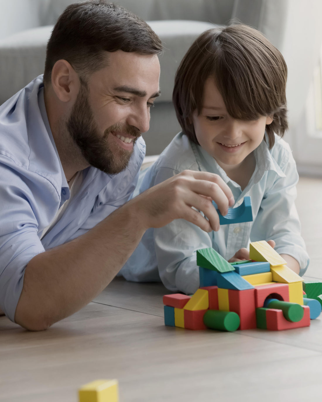 Father teaching son to build a tower from colorful blocks