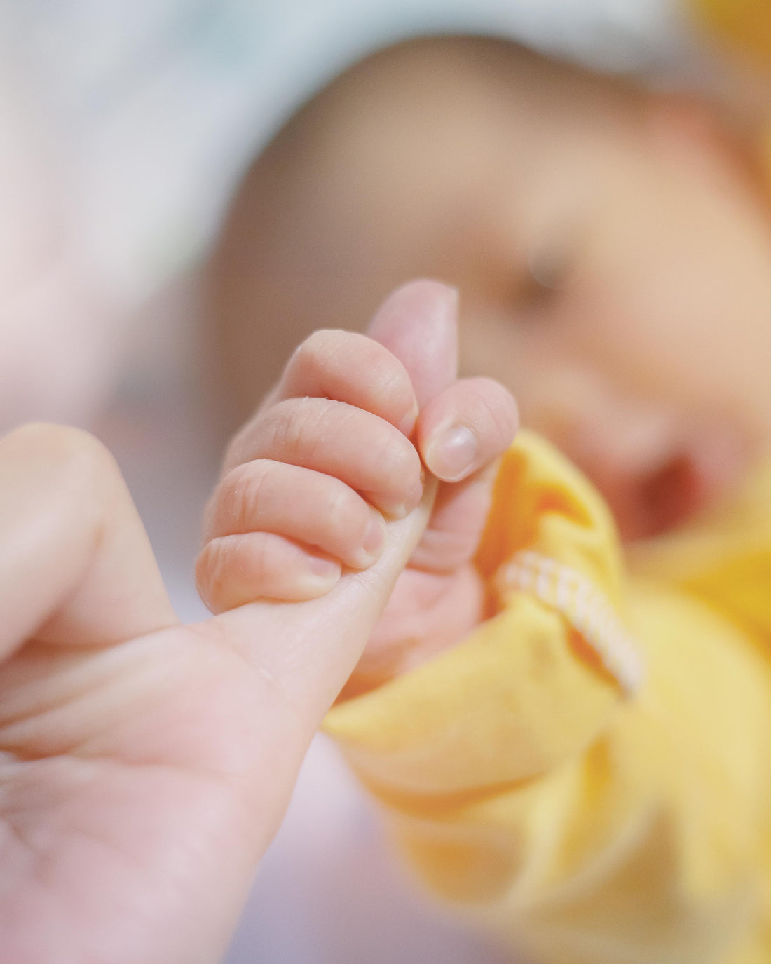 Newborn baby touching his mother's hand