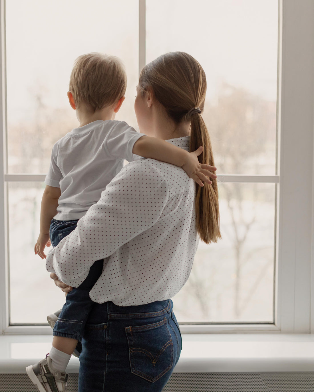 Mother holding her baby quietly by a window