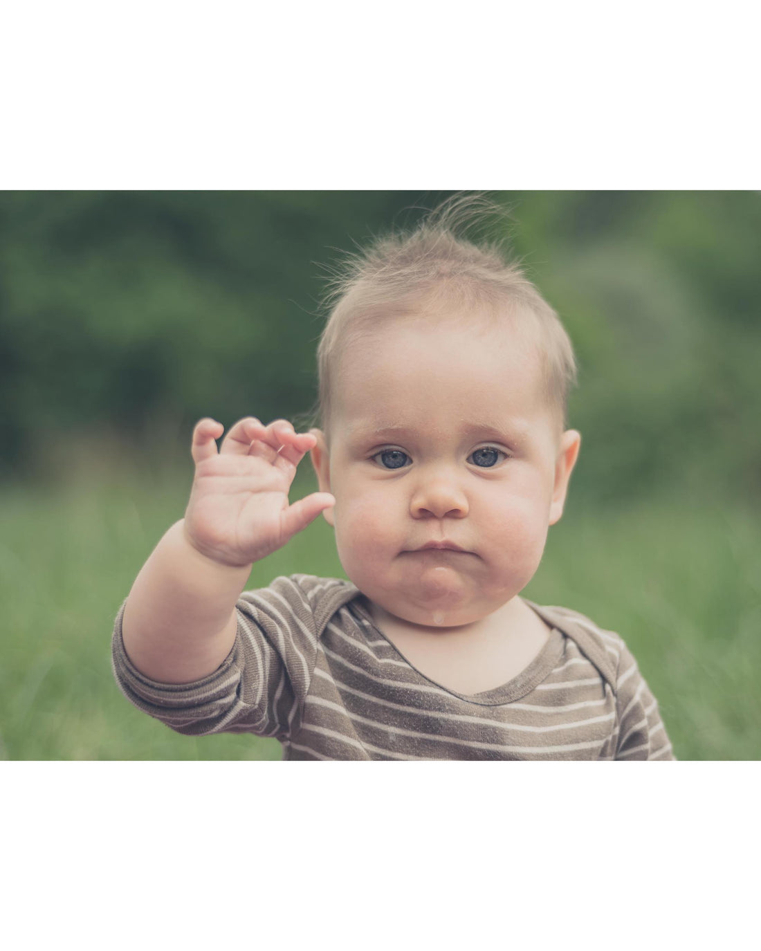 Baby waving hello outdoors in nature