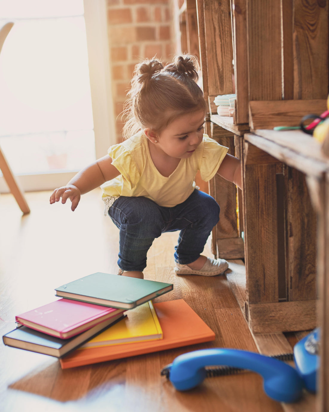Toddler taking books off the shelf at kindergarten