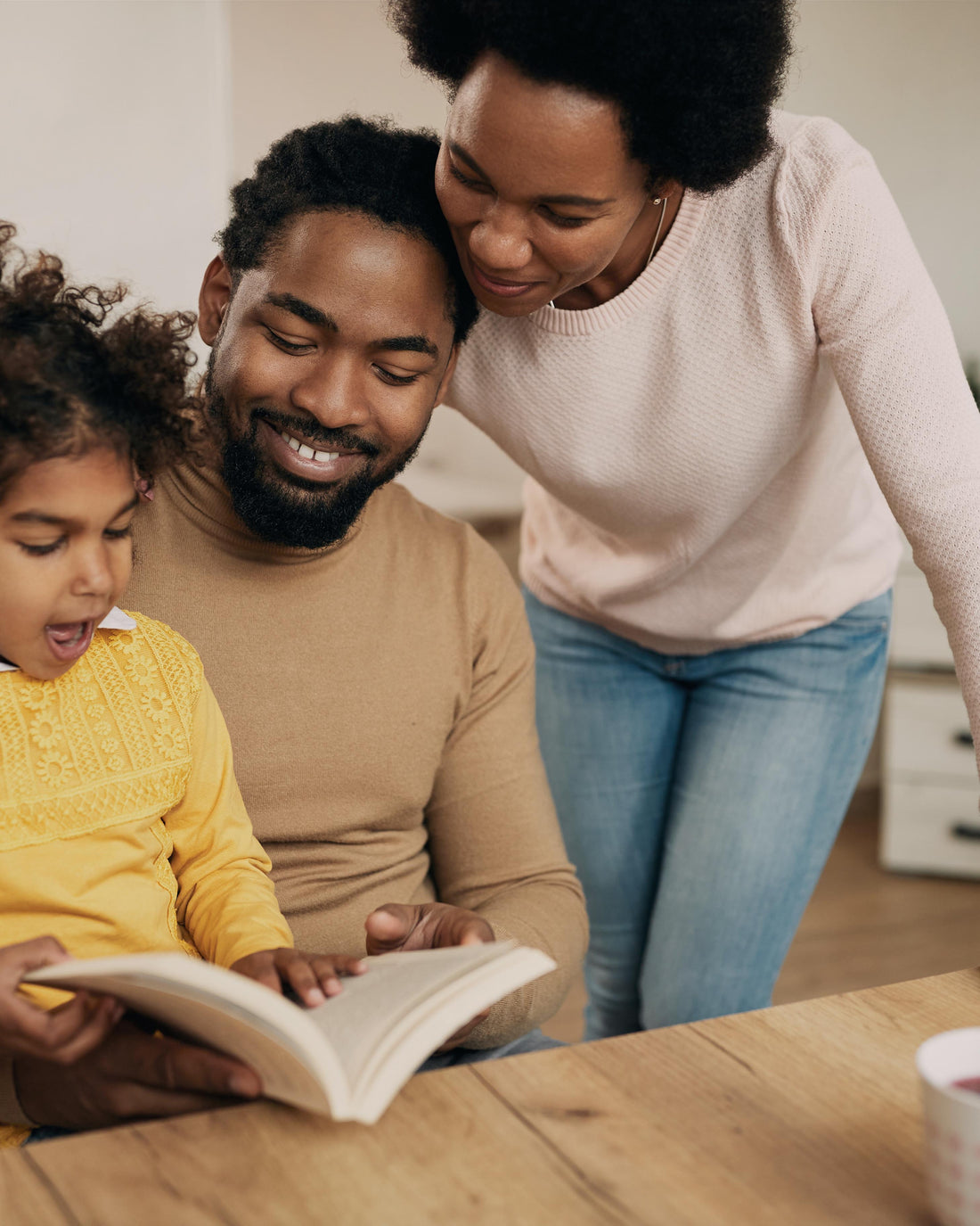 Parents reading a book with their daughter at home