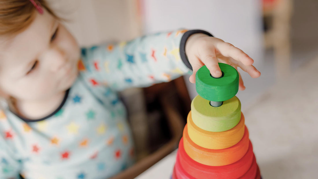 Baby girl engaged in focused play with wooden educational toys