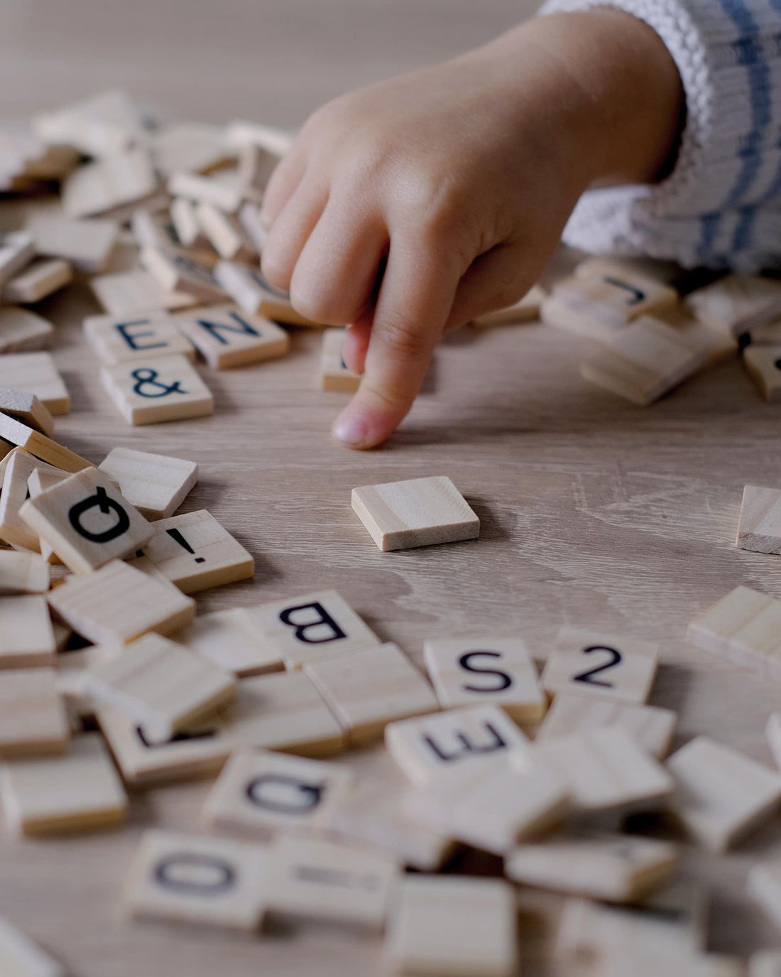 Focused child playing quietly with wooden alphabet blocks in a calm learning space