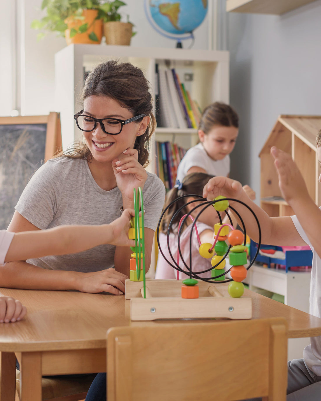 Preschool teacher with children playing with wooden toys in a classroom