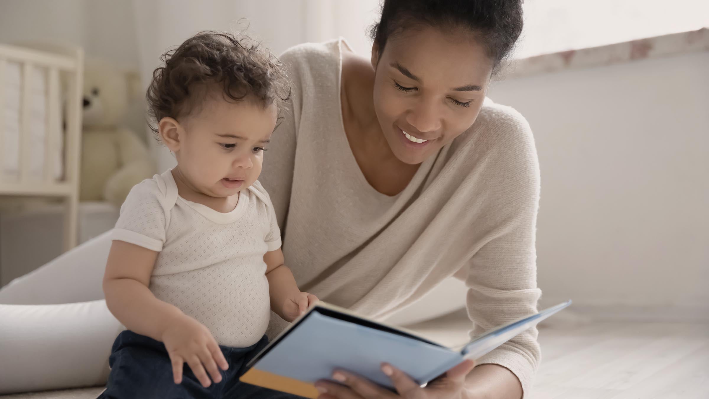 Mother reading a picture book with her baby on the floor