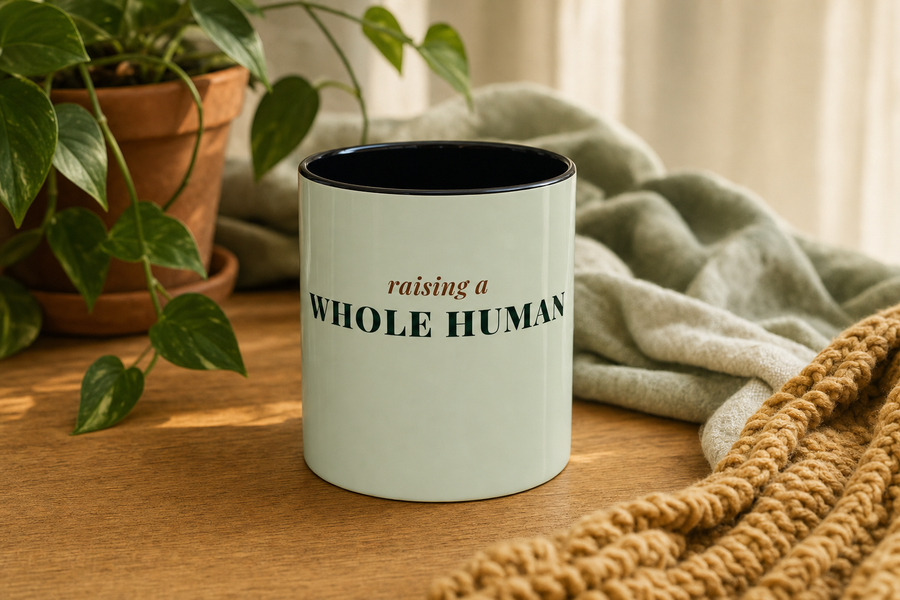Raising a Whole Human Coffee Mug by Nureli by Kala Library, ceramic mug styled on a warm oak table in soft morning light, premium lifestyle photo